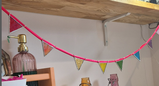 Stained glass bunting, the triangles are the colours of the rainbow, threaded on pink ribbon.