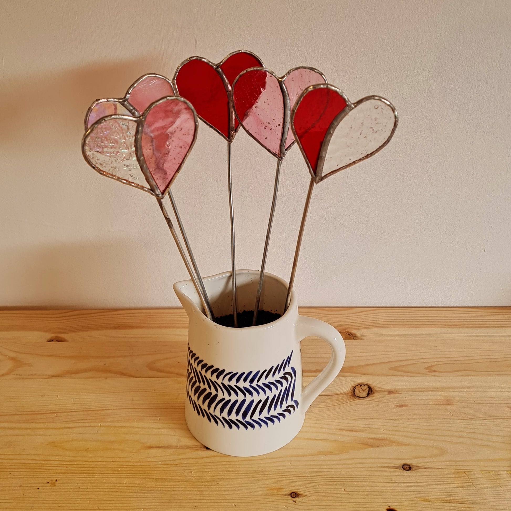 a collection of stained glass hearts on metal rods