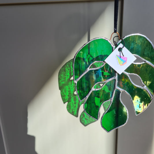 Iridescent green staines glass monstera leaf. hangin from a copper wire.